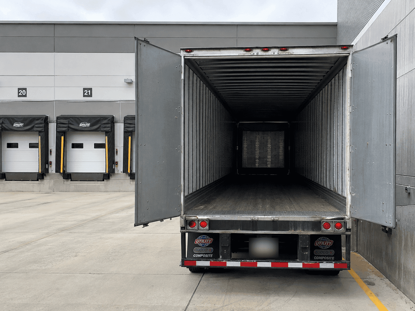Empty 53-foot dry van trailer with doors open at a loading dock